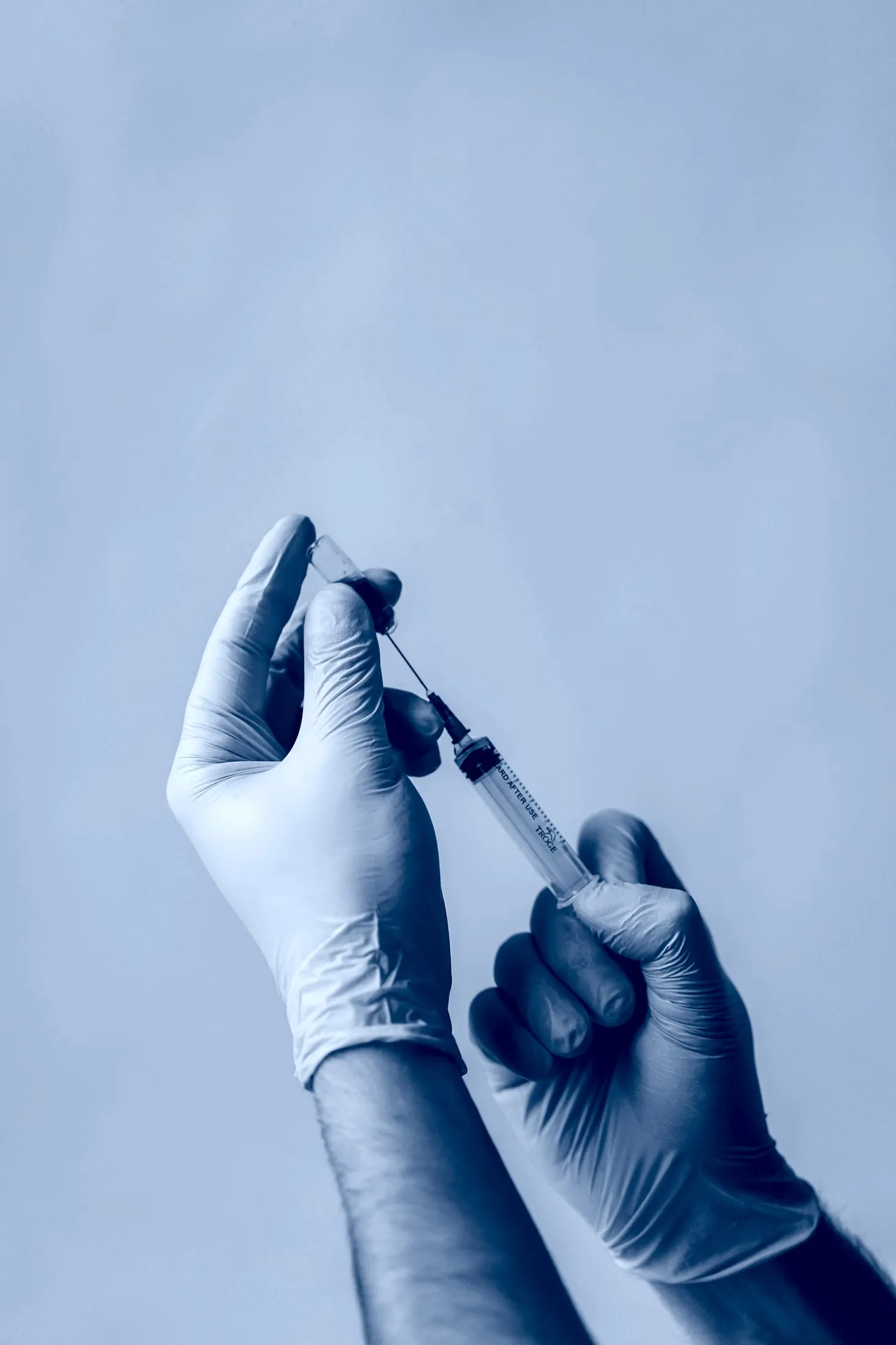 Profissional de saúde aspirando medicamento de um frasco-ampola